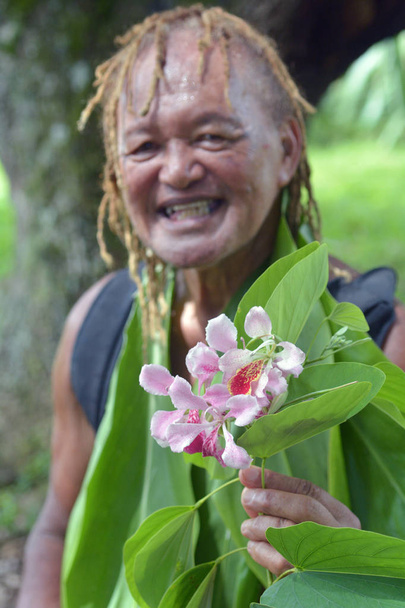 Happy Olde aged Pacific Islander man gives an exotic flower on e - Photo, Image