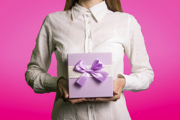 Uma jovem está segurando uma caixa de presente em um fundo rosa. O fac
 - Foto, Imagem