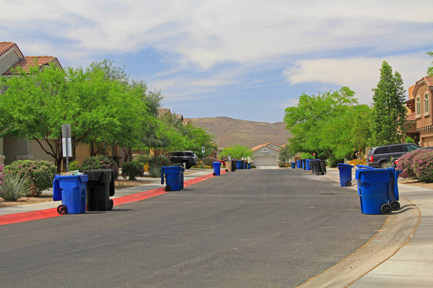 Los botes de basura azules bordean la calle el día de la basura en un vecindario de Tucson con espacio para copiar el cielo azul
. - Foto, imagen