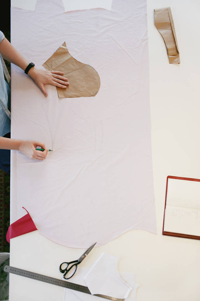 Женский портной делать узоры для шитья на столе
 - Фото, изображение