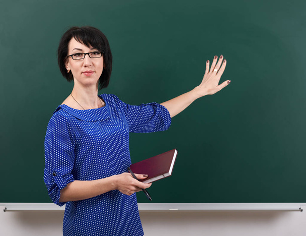 жінка-вчитель позує на крейдяній дошці, концепція навчання, зелений фон, студійний знімок
 - Фото, зображення