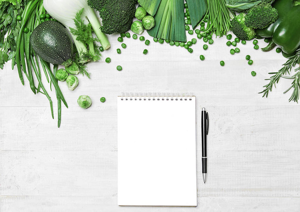 Lista de compras. Legumes verdes e caderno na tabela
 - Foto, Imagem