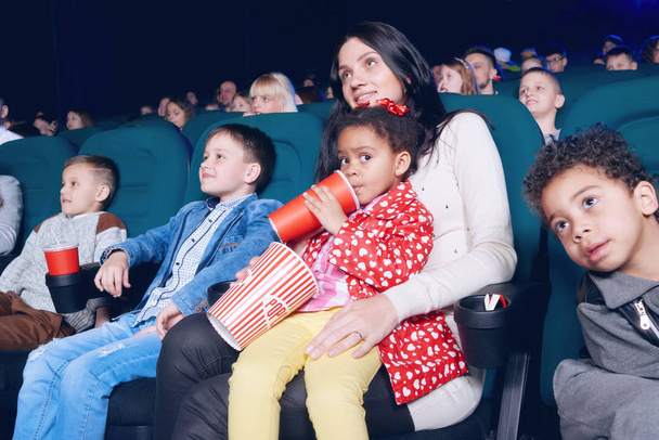 Spectators sitting in movie theatre and enjoying film, eating snacks. - Фото, зображення