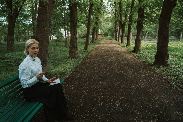 woman reads a paper letter on a bench - Fotó, kép