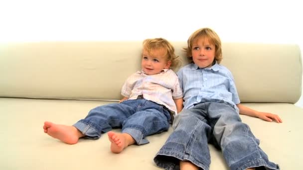 2 つの金髪の少年が白の背景にソファの上に横たわる - 映像、動画