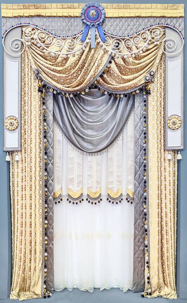 宮殿風の豪華なインテリア。中立的な灰色の挿入とゴールド カラーの生地で作られたカーテン。ラインス トーン、縁とサテンのリボンで飾られた飾り板を考え出した多階層.  - 写真・画像