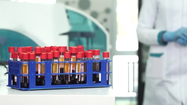 Foto recortada de un científico con guantes protectie que trabaja con tubos de análisis de sangre
 - Metraje, vídeo