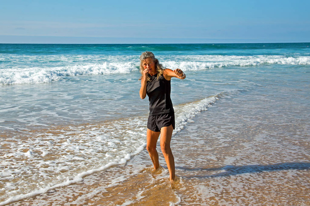 Urheilullinen kypsä nainen tekee kickbox koulutusta rannalla
 - Valokuva, kuva