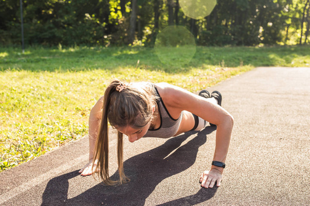 Fitness woman doing push-ups during outdoor cross training workout. Beautiful young and fit fitness sport model training outside in park - Photo, Image
