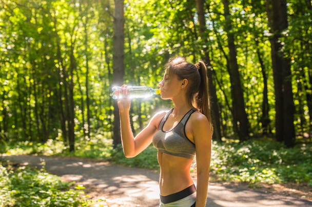 Donna sportiva che beve acqua all'aperto nella giornata di sole. - Foto, immagini