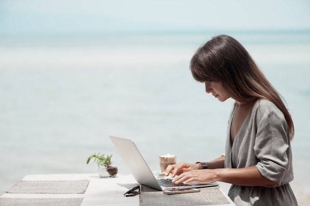 Jeune belle fille assise dans un café et travaillant sur ordinateur - Photo, image