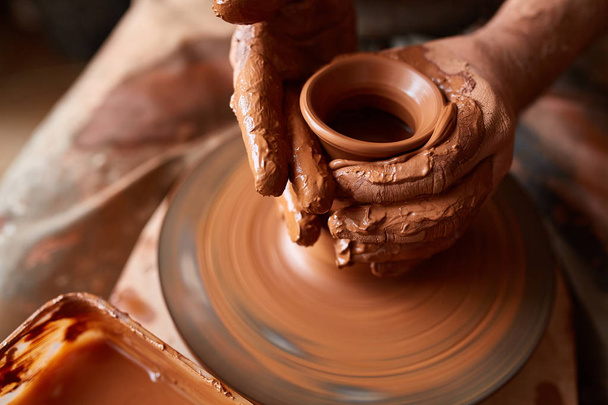 Close-up hands of a male potter in apron molds bowl from clay, selective focus - Photo, image