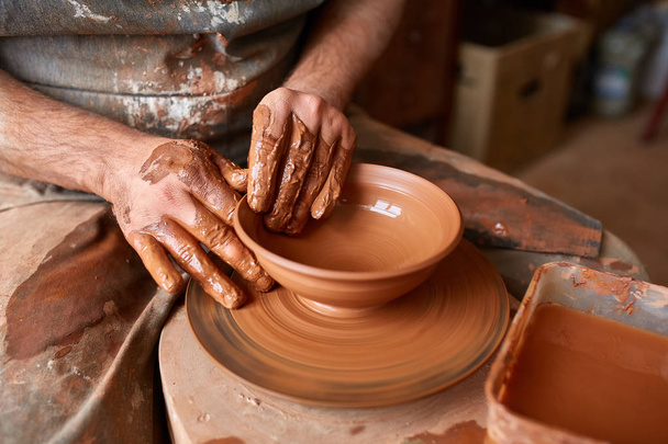 Close-up hands of a male potter in apron molds bowl from clay, selective focus - Foto, Imagen