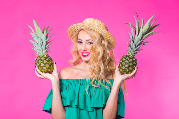 Porträt einer glücklichen Frau und Ananas auf rosa Hintergrund. Sommer, Ernährung und gesunder Lebensstil - Foto, Bild