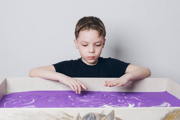 Хлопчик звертає його пальці на столі піску - Фото, зображення