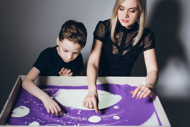 Woman and a boy draw on an interactive sand table - Fotó, kép