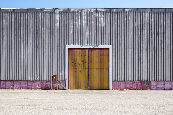 工業団地の入り口のドアに板金工場外壁。工場の建物の赤いドア. - 写真・画像