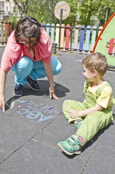 Mamá y el niño lindo dibujan alfabeto con tiza de colores sobre asfalto. Actividades de verano y juegos creativos para niños pequeños. Tiempo familiar de calidad. Feliz día de las madres. Madre e hijo juntos se divierten
.  - Foto, Imagen