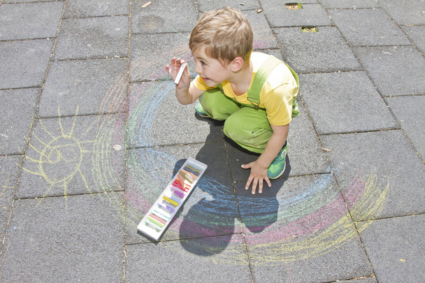 Söpö poika piirtää värikkäillä liituilla asfaltilla. Kesätoimintaa ja luovia pelejä pienille lapsille. Lapsella on hauskaa yhdessä. Koulu ja loma konsepti. Koulutuksen käsite
.  - Valokuva, kuva