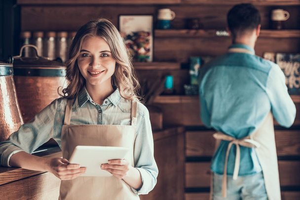 Portrait of beautiful barista in apron with tablet in cafe. - Zdjęcie, obraz