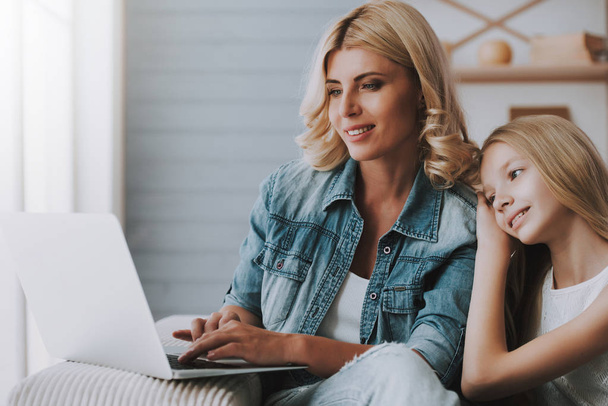 Blonde woman with little girl browsing internet pages on laptop. - Foto, Bild
