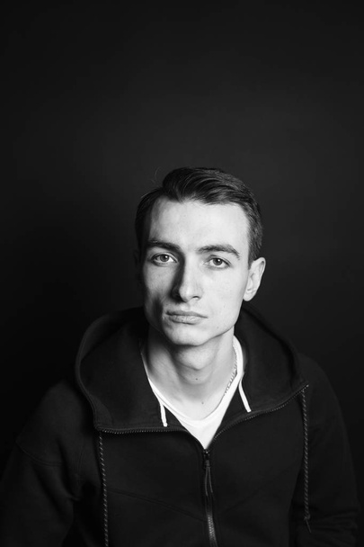 Ασπρόμαυρο πορτρέτο ενός νεαρού άνδρα σε ένα μαύρο φούτερ - Φωτογραφία, εικόνα