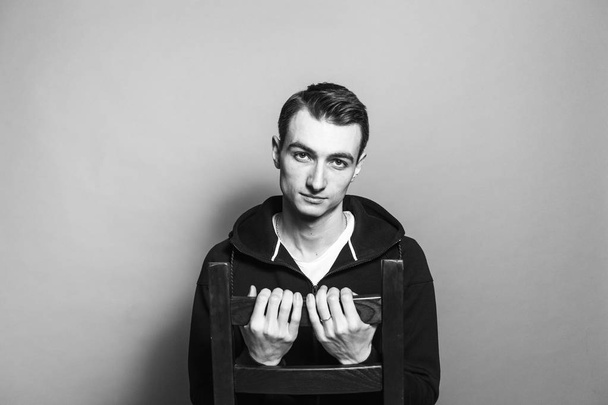 Zwart-wit portret van een jonge man in een zwart sweatshirt - Foto, afbeelding