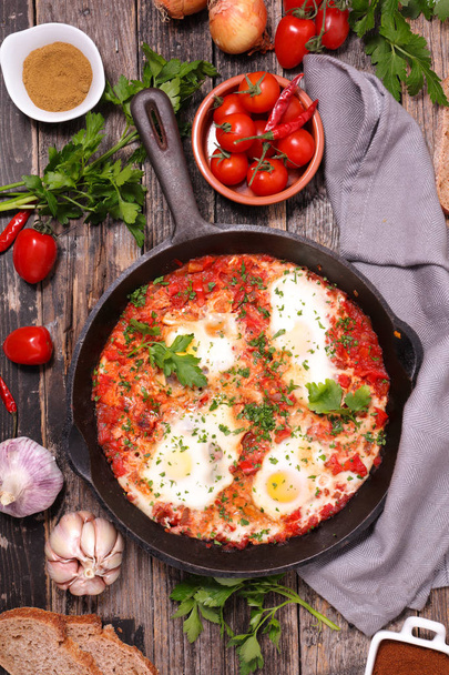 baked eggs with tomatoes and bell pepper on wooden table  - Foto, Bild