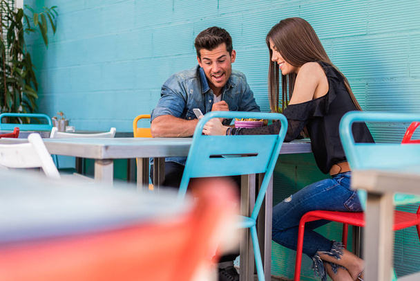 feliz jovem casal assentos em um restaurante com um smartphone
 - Foto, Imagem