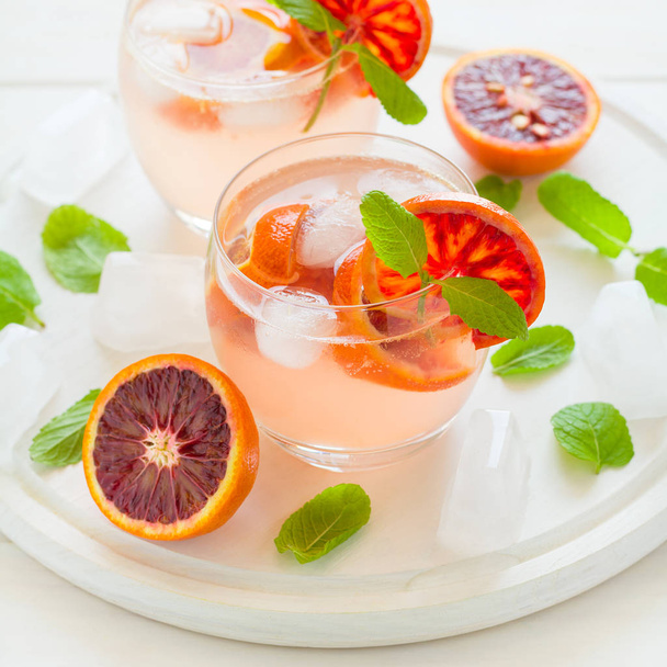 Blood orange cocktail with slices of orange on white wooden background - Foto, Imagen