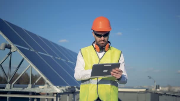 A worker uses tablet, counting solar panels on a roof. 4K. - Video