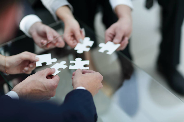 Business people holding jigsaw puzzle. - Foto, Imagen