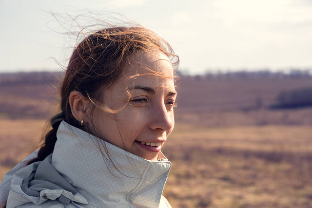 Portrét happy krásná dívka cestovatelů úsměvu, vítr fouká vlasy, slunce svítí Selektivní ostření - Fotografie, Obrázek