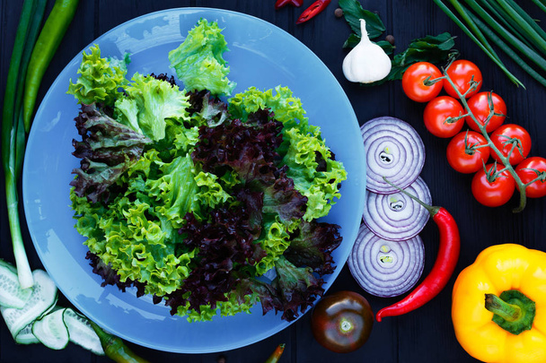 Lettuce salad on blue plate, decorated with various tomatoes, on - Photo, Image