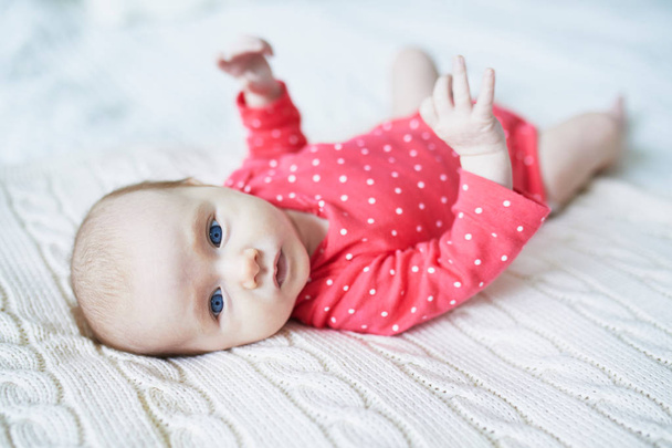 Adorable bébé fille de deux mois relaxant dans la chambre sur une couverture tricotée par un matin ensoleillé
 - Photo, image