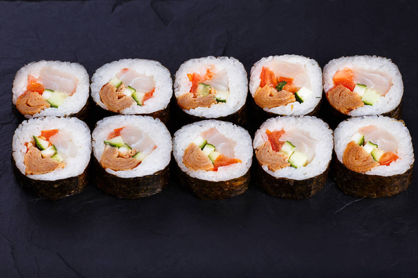 Appetizing fresh maki sushi roll with omelet served on black sla - Фото, изображение