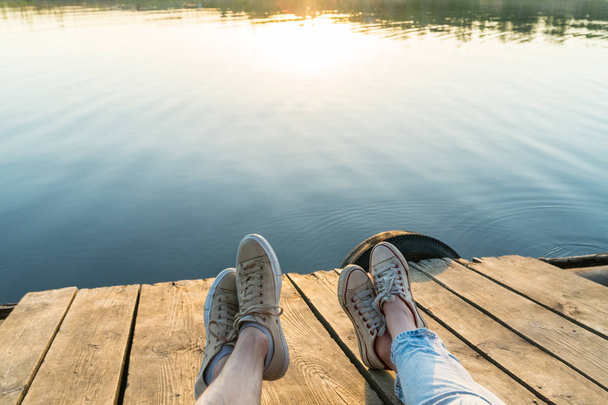 Lifestyle view of a couple's legs wearing sneakers on a wooden p - Fotografie, Obrázek
