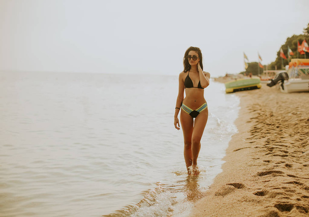 Fit a sportovní mladá žena v plavkách relaxaci na pláži na léto - Fotografie, Obrázek
