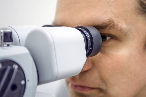 Lääkäri katsoo lääketieteellistä silmälaitetta näön tarkistamiseksi
 - Valokuva, kuva