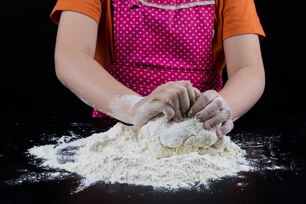 Kneading dough on a black table in a bakery. Baker's hands prepa - Φωτογραφία, εικόνα