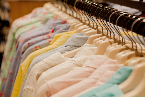 Colorful women's shirts on hangers in a retail shop. Fashion and shopping concept. - Photo, Image