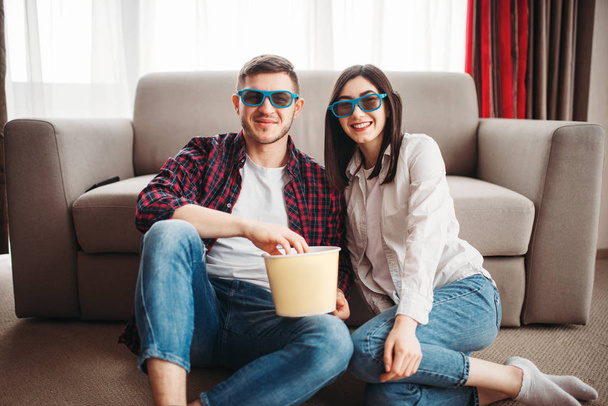 mladý pár v 3d brýle sedí na gauči a sledování televize s popcorn doma - Fotografie, Obrázek
