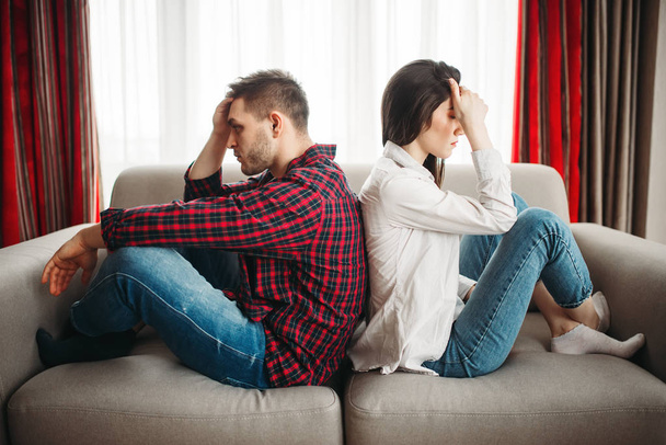 young couple sitting back to back on couch, bad relationship. Unhappy man and woman in quarrel - Photo, Image