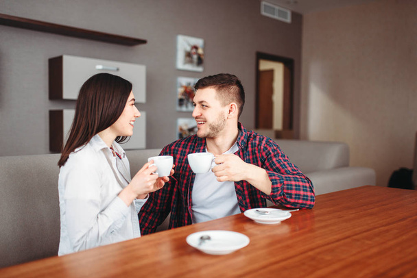 νέοι ευτυχισμένη αγάπη ζευγάρι πίνει καφέ στο ξύλινο τραπέζι στο σπίτι  - Φωτογραφία, εικόνα