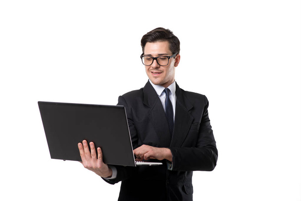 νεαρός επιχειρηματίας στην ισοπαλία και μαύρο κοστούμι χρησιμοποιώντας φορητό υπολογιστή, απομονώνονται σε λευκό φόντο - Φωτογραφία, εικόνα