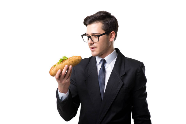 ネクタイと黒のスーツ、白い背景で隔離のホットドッグを食べる青年実業家 - 写真・画像