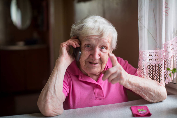 yaşlı kadın görüşmeler duygusal bir cep telefonu. - Fotoğraf, Görsel
