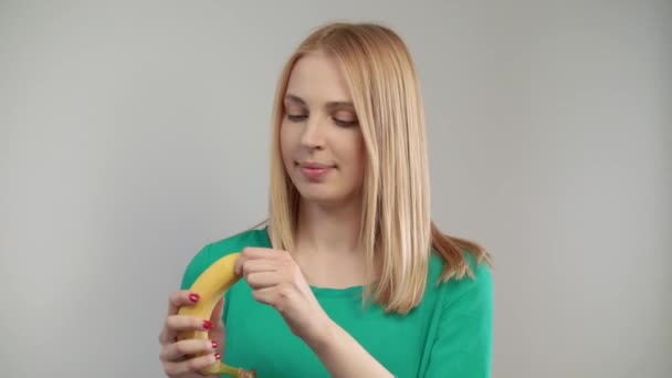 Vicino alla donna bionda che mangia banana. Ritratto di ragazza bionda che morde frutta matura
 - Filmati, video