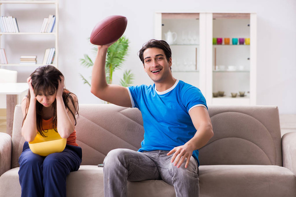 Egy férfi amerikai focit néz a feleségével. - Fotó, kép