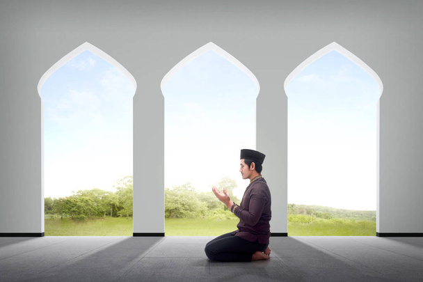 Side view of asian male muslim praying to god inside the mosque - Foto, imagen
